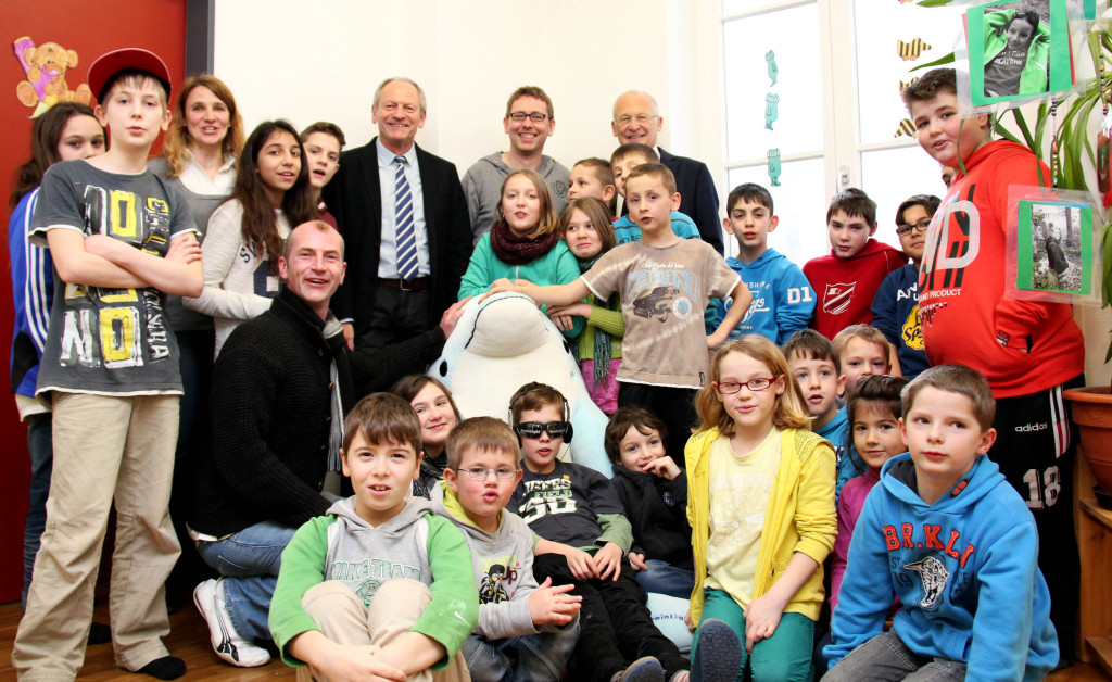 Der neue "Entspannungsdelfin" wird umringt von Kindern des Horts Zollergarten, ihrer Hortleiterin Brigitte Fakler (Dritte von links), Oberbürgermeister Dr. Ivo Holzinger (rechts hinten), Dirk Merkwitz (links daneben) und Markus Baur (links kniend) von der "Memo Lounge" und dem Referatsleiter für Jugend und Soziales, Manfred Mäuerle (zwischen Baur und Merkwitz).