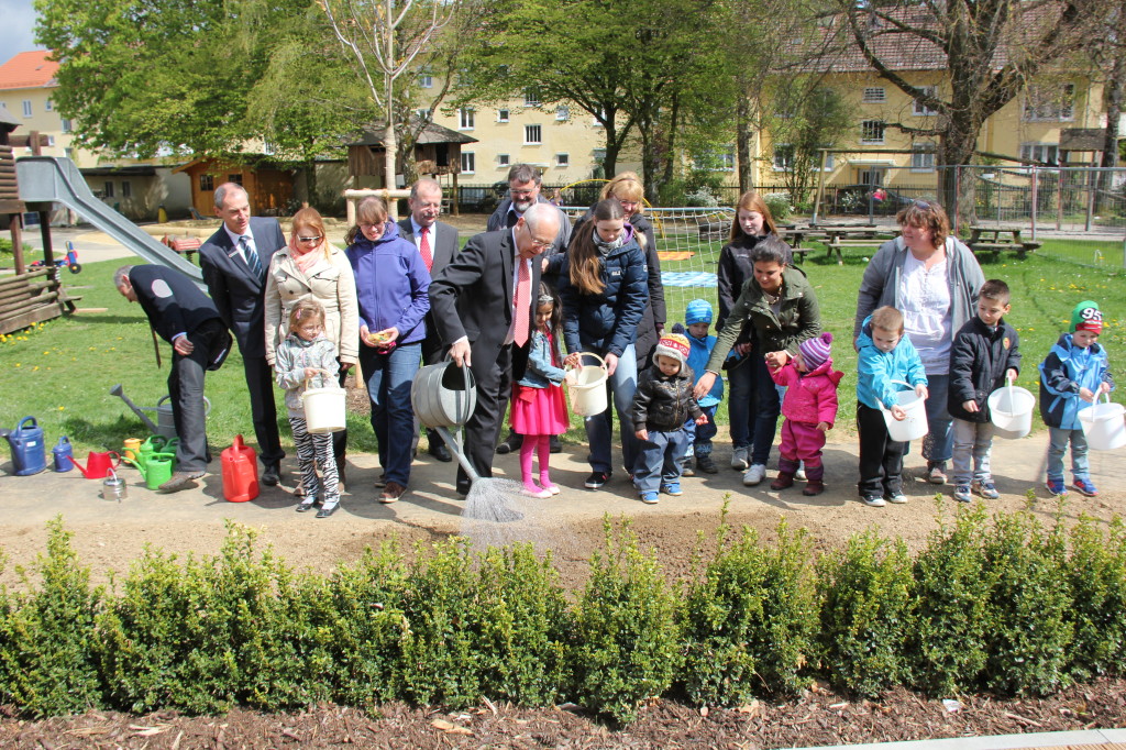 Beim Wildblumen sähen und gießen auf der Spielwiese der Kindertageseinrichtung in der Westermannstraße werden die Kinder und die Kindergärtnerinnen unterstützt von (von links): Manfred Mäuerle (Sozialreferatsleiter), Anton Groß (Sparkasse),Thomas Munding (Sparkassenchef), Oberbürgermeister Dr. Ivo Holzinger, Rudolf Schnug (Garten- und Friedhofsamtsleiter, dahinter), Maria Schmölzing (Stadtratsreferentin, leicht verdeckt) und Andrea Walzer (Kindergartenleiterin, ganz rechts).