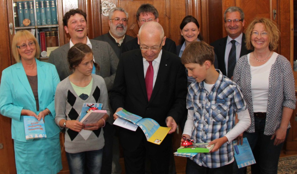 Bei der Präsentation des noch druckfrischen Kinderfestheftchens 2014 (v.l.n.r.): Gerlinde Arnold, Vorsitzende des Kinderfestausschusses, Nora Hinrichs, Christoph Baur (Referent für Heimatfeste - dahinter), Stadtrat Edmund Güttler (Grund- und Mittelschulen), Oberbürgermeister Dr. Ivo Holzinger, Stadtrat Bernhard Thrul (Förderzentrum Reichshainschule, hinten), Michael Tschugg, Lehrerin Stephanie Krüger, Schulleiter Willi Seitz und Andrea Karasch, die stellv. Schulleiterin und Kinderfestbeauftragte der Reichshainschule. Foto: Klett/Pressestelle Stadt Memmingen.